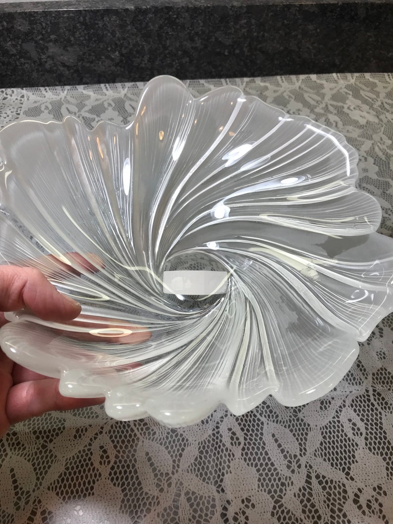 Puede incluir: Un cuenco de vidrio transparente con un dise&ntilde;o de espiral. El cuenco tiene forma de flor con m&uacute;ltiples p&eacute;talos.