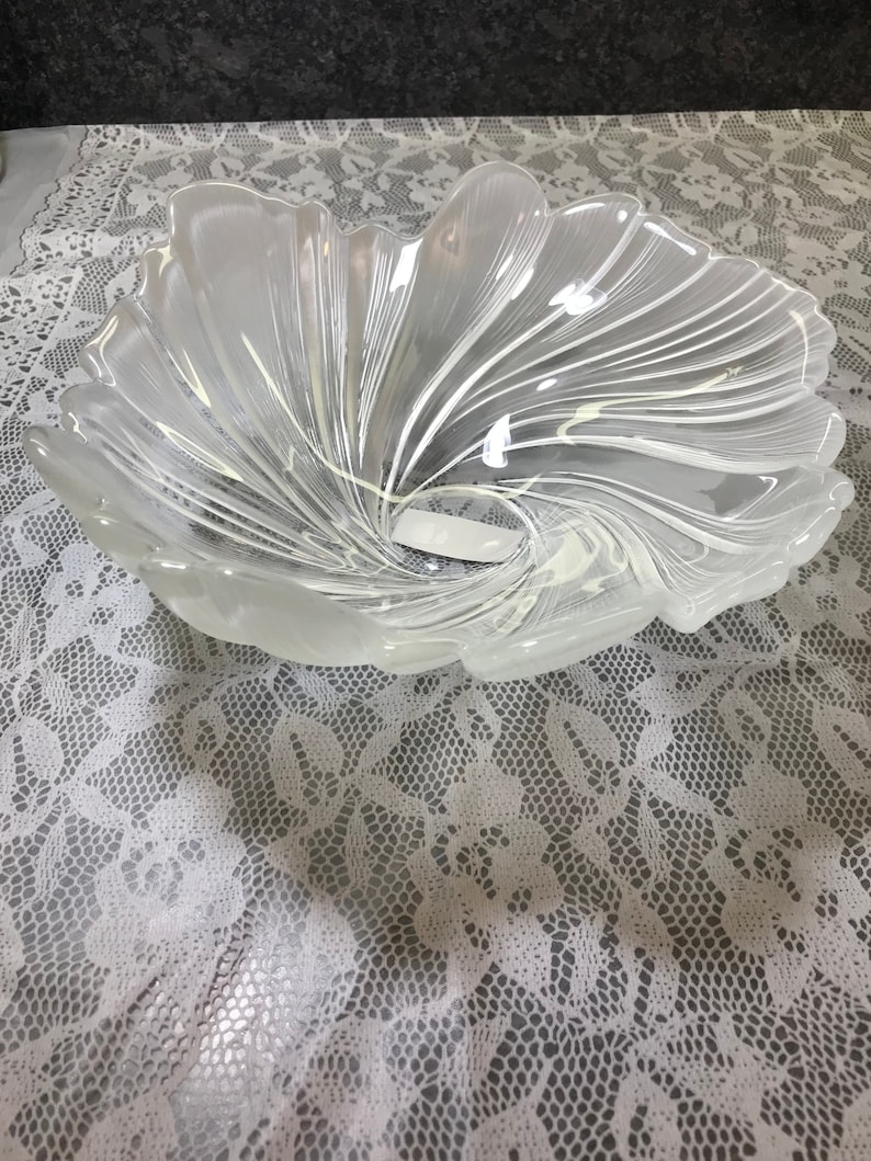 Puede incluir: Un cuenco de vidrio transparente con un dise&ntilde;o de espiral. El cuenco tiene forma de flor y tiene una abertura ancha y poco profunda.