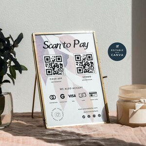 May include: A white sign with a gold frame and a pink and white watercolour background. The sign says "Scan to Pay" and has two QR codes, one for Cash App and one for Venmo. The sign also lists other payment methods, including Mastercard, Google Pay, Visa, Cash, and Credit Card. The sign also includes a website address and social media icons.