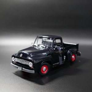 Peut inclure: Un modèle de camionnette Ford de 1953 noir avec une calandre chromée brillante, des pare-chocs argentés et des roues rouge vif. Le véhicule miniature comprend des fenêtres transparentes, des rétroviseurs et une plaque d'immatriculation 1953.