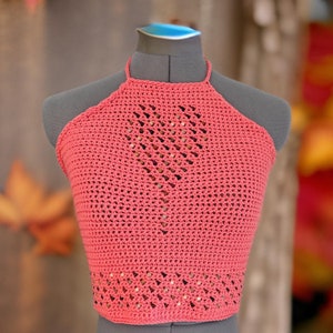 Può includere: Un top halter in crochet rosa corallo con un design geometrico e dettagli perlati.
