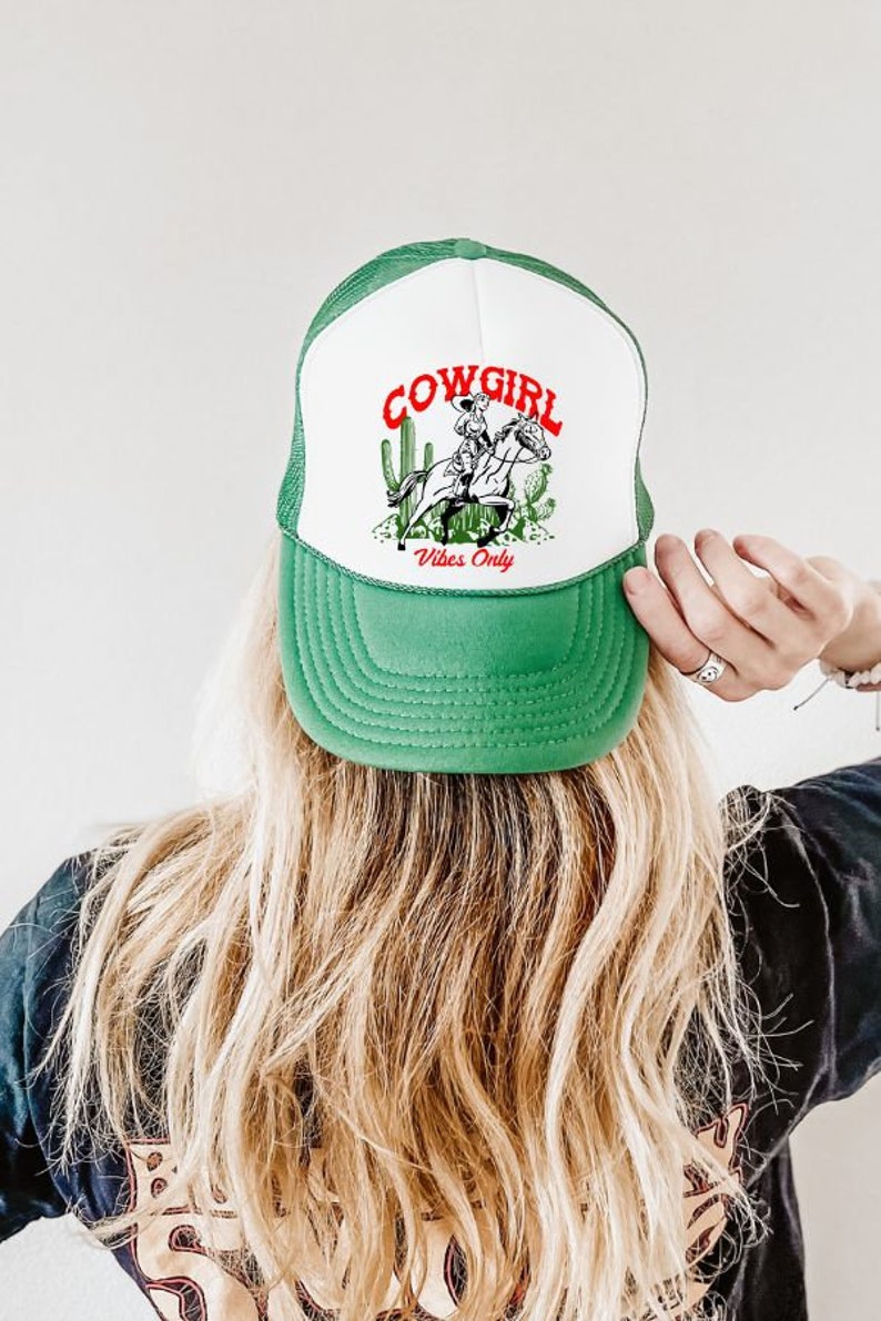 May include: Green and white trucker hat with a cowgirl riding a horse and cactus graphic. The text "COWGIRL Vibes Only" is printed on the hat.