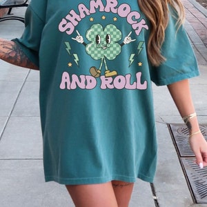 May include: Teal blue oversized t-shirt with a cartoon shamrock graphic and the text "Shamrock and Roll".