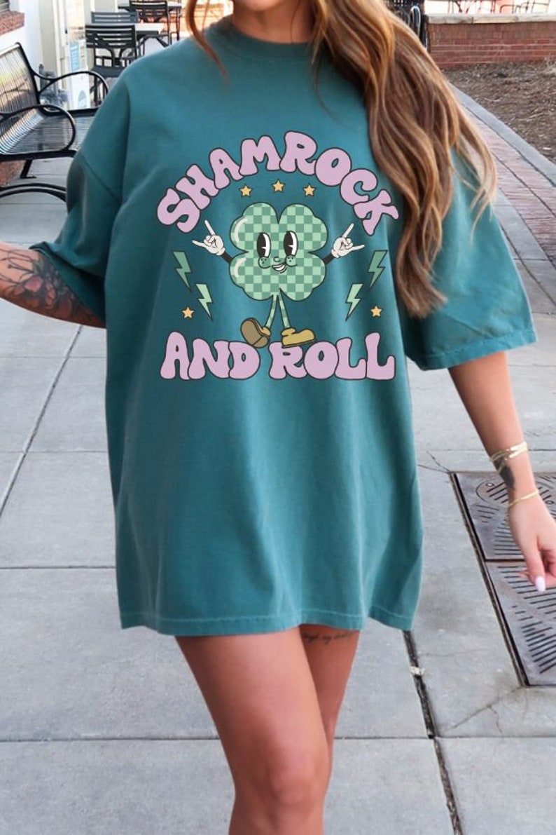 May include: Teal blue oversized t-shirt with a cartoon shamrock graphic and the text "Shamrock and Roll".