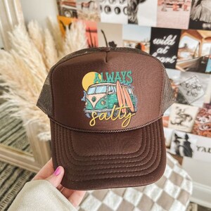 May include: Brown trucker hat with a green and yellow vintage van graphic and the text "Always Salty".
