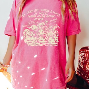 K&ouml;nnte beinhalten: Rosafarbenes Oversize-T-Shirt mit einer Vintage-Grafik von Pferden und einem Zitat: "Seid vollkommen dem&uuml;tig und sanftm&uuml;tig. Seid geduldig und ertragt einander in Liebe. Epheser 4,2".