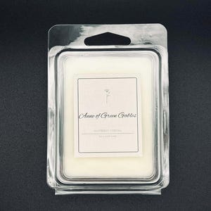 May include: A rectangular wax melt in a clear plastic clamshell package. The wax is off-white, with a label that reads "Anne of Green Gables" and "Raspberry Cordial". The package has a hole for hanging.