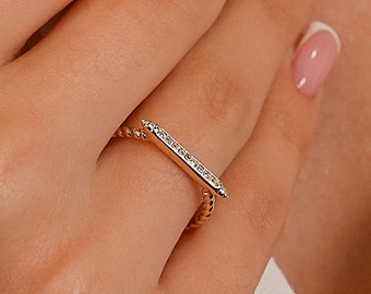 May include: A gold ring with a thin bar set with small diamonds. The bar is pointed at one end.