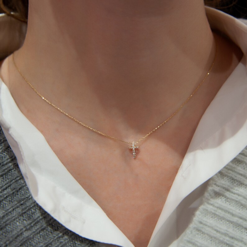 Puede incluir: Un delicado collar de cadena de oro con un peque&ntilde;o colgante de cruz engastado con diamantes.