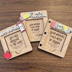 May include: Three wooden teacher appreciation gifts. Each frame has a cutout for a photo and includes a pencil or apple accent. The frames have text that reads, "Your influence could never be erased!" and "You are awesome, to the core!"