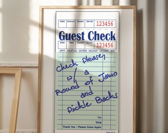 May include: A framed green and white guest check with handwritten text that says "Check please w/ a round of Jamo and Pickle Backs". The check has the text "Guest Check" at the top and the numbers "123456" in red.