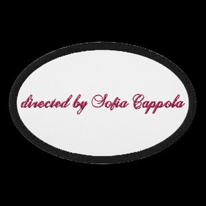 May include: White oval patch with a black border. The text "directed by Sofia Coppola" is embroidered in pink.