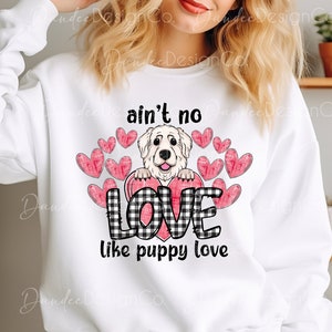 May include: White sweatshirt with a black and white checkered heart and the text "ain't no love like puppy love". A white dog with pink ears is peeking out from behind the heart.