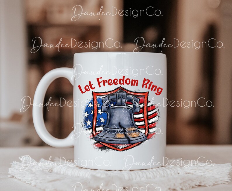 Puede incluir: Taza de cer&aacute;mica blanca con un dise&ntilde;o de bandera estadounidense rojo, blanco y azul con una campana de la Libertad de dibujos animados. El texto "Let Freedom Ring" est&aacute; escrito en rojo en la taza.