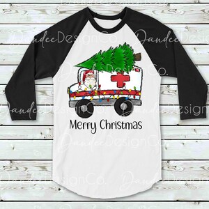 Pu&ograve; includere: Una maglietta da baseball bianca e nera con un'ambulanza rossa e bianca con un albero di Natale in cima. Babbo Natale guida l'ambulanza. Il testo "Buon Natale" &egrave; stampato sulla maglietta.