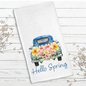 May include: A blue vintage truck with a bed full of watercolor flowers. The truck has a white background with the text "Hello Spring" in blue.