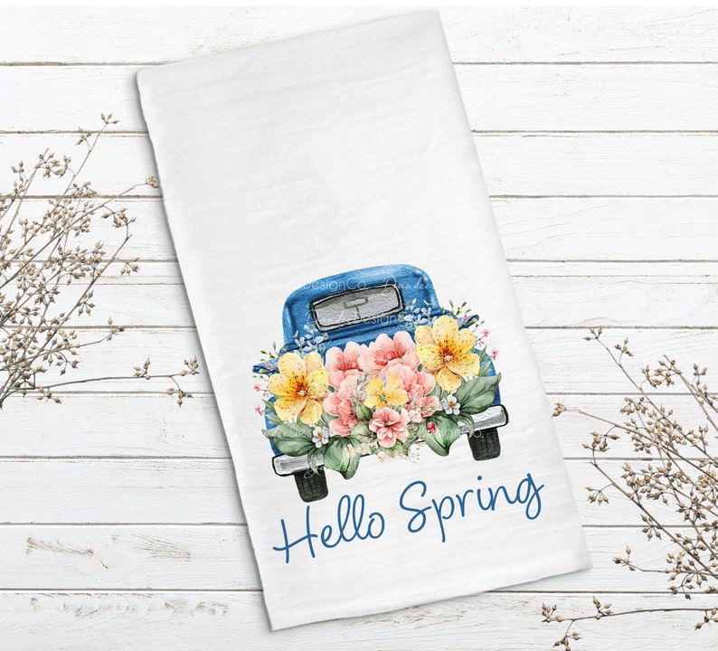 May include: A blue vintage truck with a bed full of watercolor flowers. The truck has a white background with the text "Hello Spring" in blue.