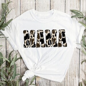 Puede incluir: Camiseta blanca con la palabra "MAMA" en letras negras delineadas con un estampado de leopardo marr&oacute;n y blanco.