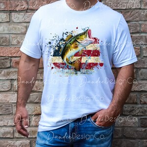 May include: A white t-shirt featuring a graphic design of a fish leaping from the water in front of an American flag with red, white and blue colours. The design has a distressed look with splattered paint.