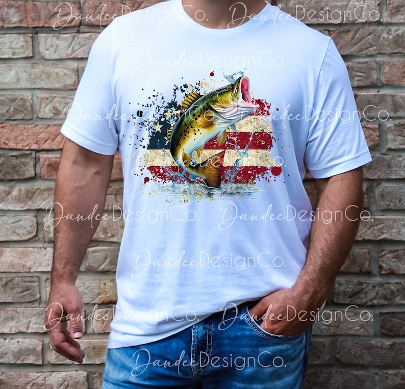 May include: A white t-shirt featuring a graphic design of a fish leaping from the water in front of an American flag with red, white and blue colours. The design has a distressed look with splattered paint.
