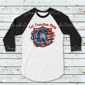 Puede incluir: Una camiseta de b&eacute;isbol blanca y negra con un dise&ntilde;o de bandera estadounidense roja, blanca y azul. La bandera tiene una campana en el centro y el texto "Let Freedom Ring" arriba.