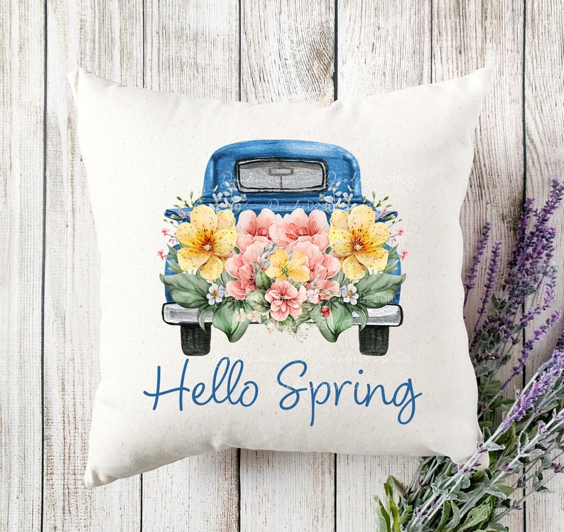 May include: A blue pickup truck with a bed full of yellow and pink flowers. The truck has the words "Hello Spring" written on the front.