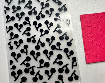 Op de afbeelding: Een transparante plastic vel met een herhalend patroon van zwarte kersen. Het vel is ontworpen voor knutselen en stempelen.