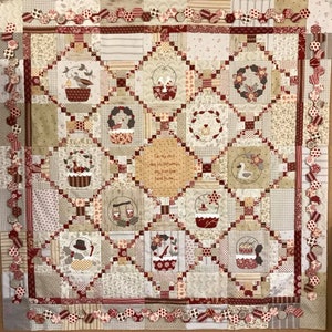 May include: A beige and red patchwork quilt with a white text panel that reads "On the twelfth day of Christmas, my true love gave to me..." The quilt is decorated with various embroidered images of birds, baskets, and wreaths.