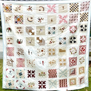 May include: A white quilt with a patchwork design featuring various patterns and colors. The quilt is made up of 100 squares, each with a different design. The quilt is displayed on a white background.