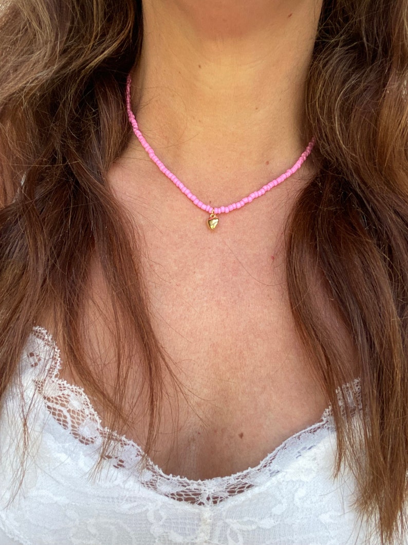 Pu&ograve; includere: Una delicata collana di perline rosa con un piccolo ciondolo a forma di cuore dorato. La collana &egrave; a girocollo, con minuscole perline rosa infilate insieme. Il ciondolo a forma di cuore dorato pende al centro, aggiungendo un tocco di eleganza.