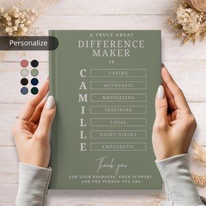 Könnte beinhalten: Ein salbeigrünes Notizbuch mit dem Text "A Truly Great Difference Maker Is" und dem Namen "CAMILLE" mit beschreibenden Wörtern geschrieben. Das Notizbuch wird von Händen gehalten, mit einer Farbpalette auf der linken Seite.
