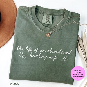 The Life of a an Abandoned Hunting Wife Comfort Colors shirt with minimalist  design. Perfect hunting season gift for wives, girlfriends, or country girls who love the outdoors. Made from 100% sustainable US cotton, garment-dyed for a soft vintage look. Available in multiple fall colors like Yam, Moss, Blue Jean, Pepper, Ivory, and Espresso. Ethically made and printed in the USA.