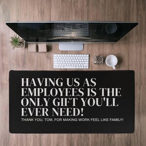 Peut inclure: Tapis de bureau noir avec du texte blanc qui dit "Avoir des employés comme nous est le seul cadeau dont vous aurez jamais besoin ! Merci, Tom, d'avoir fait en sorte que le travail se sente comme une famille !"