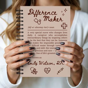 Könnte beinhalten: Ein beige Spiralnotizbuch mit dem Schriftzug "Difference Maker" in einer dekorativen Schriftart. Das Notizbuch enthält eine Definition einer Krankenschwester, mit dem Namen "Emily Watson, RN" unten. Das Cover hat braunen Text und Illustrationen.