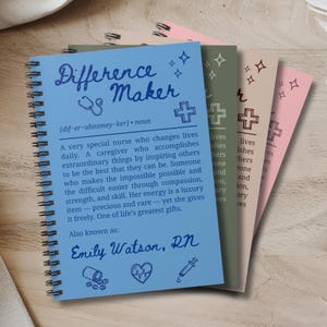 Peut inclure: Plusieurs cahiers à spirales avec l'inscription "Difference Maker" sur la couverture. Le cahier bleu contient une définition d'une infirmière. Les autres cahiers sont verts, beiges et roses. Thème médical.