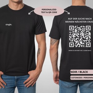 May include: Black t-shirt with the word "single" printed on the front. The back of the shirt features a QR code and German text. The shirt is a basic crew neck style.