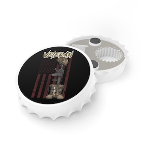 Puede incluir: Abrebotellas blanco con un diseño de bandera estadounidense en negro y rojo y la palabra "Veteran" en letras doradas. El abrebotellas presenta una silueta de soldado con un rifle y botas.