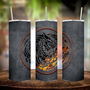 Puede incluir: Tres vasos de acero inoxidable con un acabado texturizado negro y gris. Cada vaso presenta un diseño circular con una silueta de dragón negro y llamas naranjas.