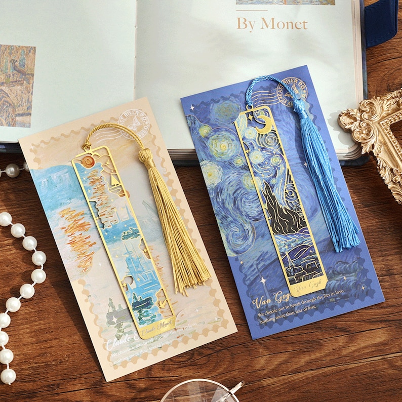 May include: Two gold metal bookmarks with colourful images and tassels. The bookmark on the left features a painting by Claude Monet and the bookmark on the right features a painting by Van Gogh. The text on the bookmark reads "We choose not to break through the ties in love, nothing matters than the feat of love."