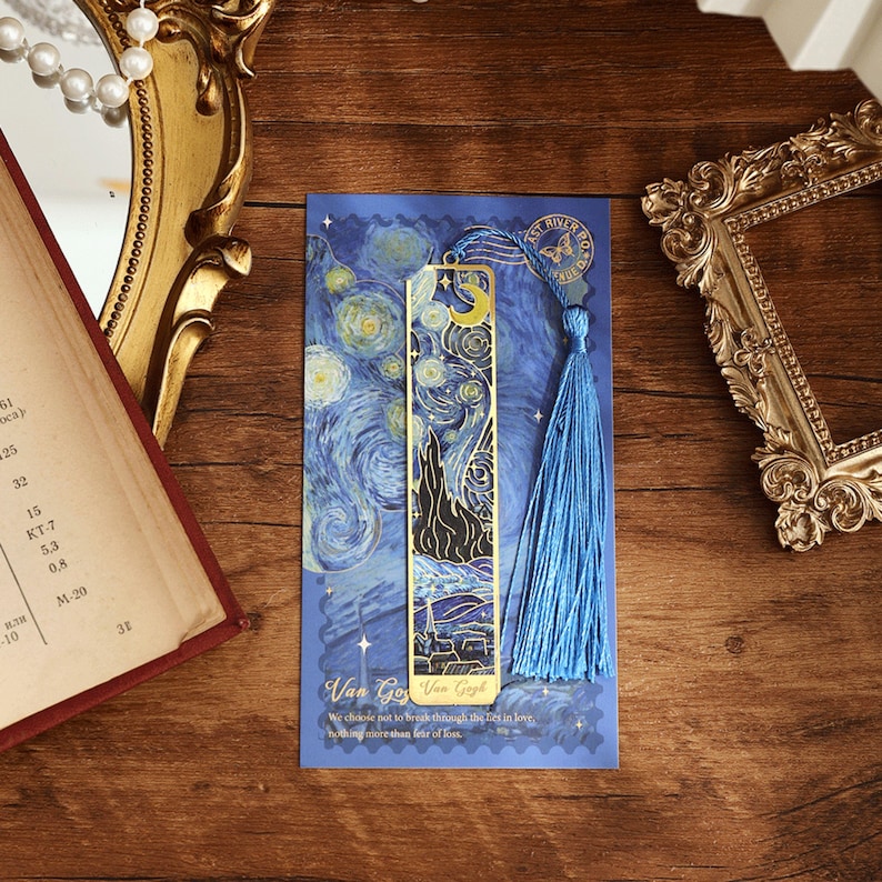 May include: A gold metal bookmark with a blue tassel. The bookmark features a reproduction of Vincent van Gogh's "Starry Night" painting. The bookmark is on a blue background with the text "Van Gogh Van Gogh" and "We choose not to break through the 25th in love, nothing more than fear of loss."