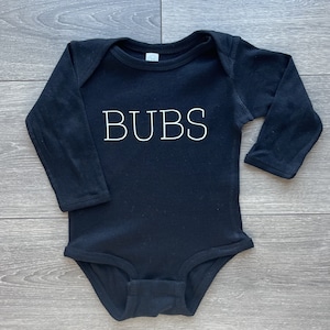 May include: Black long-sleeve baby onesie with white text that reads "BUBS".