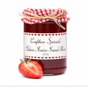 May include: A jar of red jam with a checkered lid and a label that reads "Confiture Spéciale Future Arrière-Grand-Mère 2026." A halved strawberry sits next to the jar. The label has red heart accents.