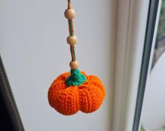 Puede incluir: Un llavero de calabaza naranja hecho a mano con ganchillo y un tallo verde. El llavero tiene cuentas de madera y un cordón naranja y verde. La calabaza está suspendida de un cierre de metal.