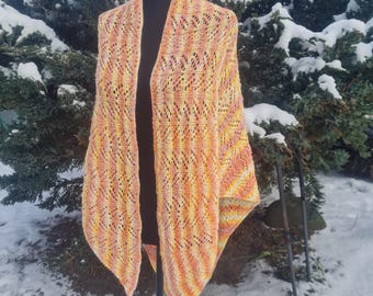 Puede incluir: Un chal triangular con un patrón de encaje en tonos naranja, amarillo y blanco. El chal se muestra en un maniquí negro sobre un fondo nevado.