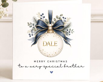 May include: A square greeting card featuring a white Christmas ornament with gold stars and the name DALE in gold lettering. The ornament is topped with a dark blue ribbon bow and green foliage. Text reads MERRY CHRISTMAS to a very special brother.