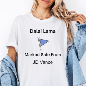 May include: White t-shirt with the text "Dalai Lama" and a blue flag icon. Below the flag is the text "Marked Safe From JD Vance".