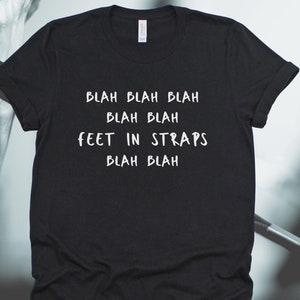 May include: Black t-shirt with white text that reads "Blah blah blah blah blah Feet in straps blah blah".