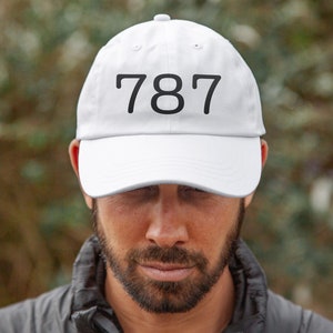 May include: White baseball cap with the number 787 printed in black on the front.