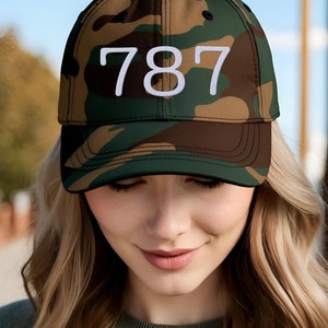 May include: A camouflage baseball cap with the number 787 embroidered in white on the front.