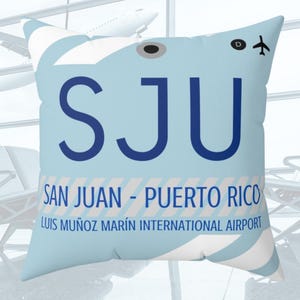 May include: A blue and white throw pillow with the airport code "SJU" and the text "San Juan - Puerto Rico Luis Muñoz Marín International Airport".